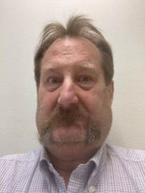 The image shows an individual with a neatly trimmed beard wearing a striped shirt.

AI-generated content may be incorrect.