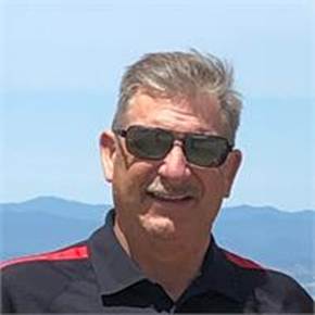 The image shows a person wearing a red shirt and black sunglasses, standing against a clear sky with distant mountains in the background.

AI-generated content may be incorrect.